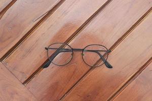 a close up of eyeglasses with black frames isolated natural patterned wooden background. photo