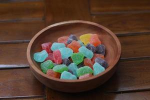 a close up of gummy candies of various colors and fruit flavors served in a wooden bowl. photo