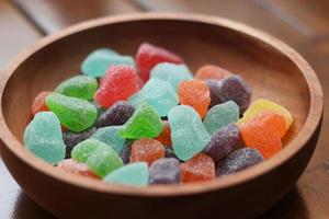 a close up of gummy candies of various colors and fruit flavors served in a wooden bowl. photo