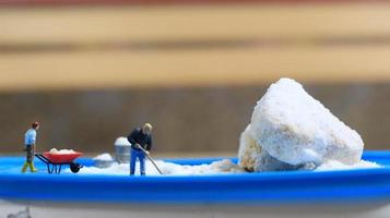 a miniature figure of a worker tidying a peanut cake sprinkled with powdered white sugar. concept of workers in the food industry. photo