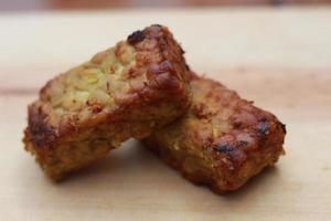 a close up of fried tempeh on a wooden cutting board. photo