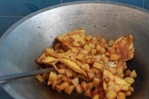 photo of cooking potatoes and omelet with spicy seasoning or balado on a frying pan. concept photo of Indonesian food.