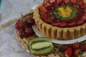 grande Fruta tarta con coberturas de fresas, uvas, kiwi y piña. sabroso, dulce y fresco. comida concepto foto. foto