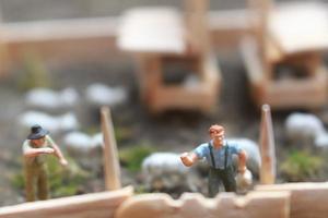 A close up of miniature figure of a goat herder feeding in a wooden cage. Shepherd concept. photo