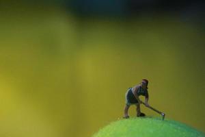 miniatura figura de un hembra granjero trabajando el tierra con un amanecer antecedentes. foto