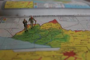 miniatura figura de un explorador posando en un mapa o atlas foto