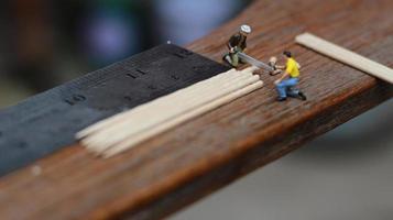 Miniature figure of a worker cutting toothpicks. carpenter activity photo concept.