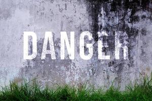 Danger text written with broken cement wall, Danger word on street. photo