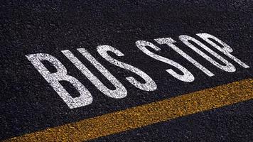 autobús detener texto escrito y amarillo línea en el la carretera en medio de el asfalto camino, autobús detener palabra en calle. foto