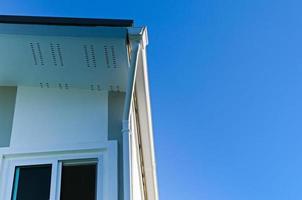 House roof with rain gutter of roof top house and large windows on blue sky background, New modern building photo