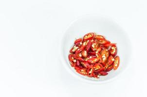 Chopped and slices of red chilli in a white cup isolated on white background,top view photo