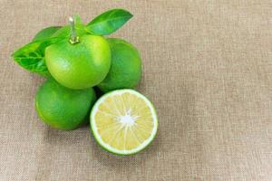 agrios fruta, composición con hojas en marrón tela antecedentes foto