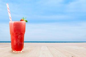 Strawberry juice smoothie in glass with fresh strawberry on table wooden with beach landscape view nature background photo