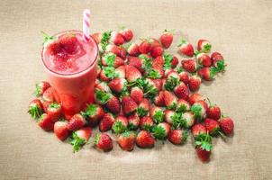 Strawberry juice smoothie in glass with fresh strawberry on traditional sack textile background.Summer refreshing healthy drink photo