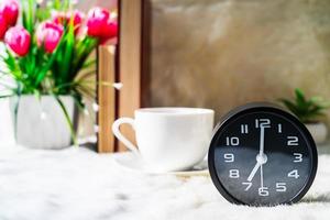 Black clock and cup of coffee photo