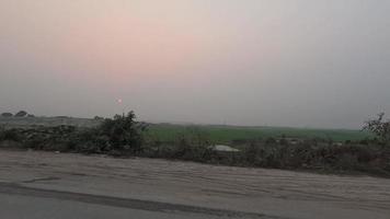 schön Sonnenuntergang Aussicht im ein ländlich Bereich 4k Video. Landschaft Straße Ausflug Aufnahmen beim Dämmerung Zeit. schön Wiese, Backstein Ofen, und Sonnenuntergang Aussicht von ein ziehen um Fahrzeug. Dorf Straße Ausflug 4k Filmaufnahme. video