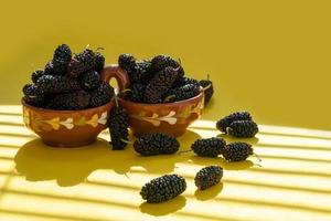 Fresh ripe mulberries fruite in a plate on a yellow background photo