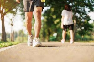 man jogging and walking on the road at morning with Energy Drink water, adult male in sport shoes running in the park outside. Exercise, wellness, healthy lifestyle and wellbeing concepts photo