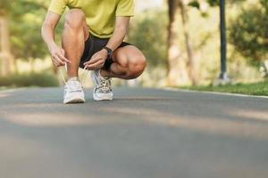 joven atleta hombre atadura corriendo Zapatos en el parque exterior, masculino corredor Listo para trotar en el la carretera afuera, asiático aptitud caminando y ejercicio en sendero en Mañana. bienestar y deporte conceptos foto