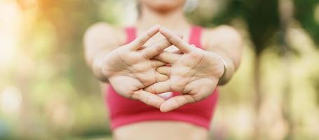 joven adulto hembra en rosado ropa de deporte extensión músculo en el parque exterior, deporte mujer calentar arriba Listo para corriendo y trotar en Mañana. bienestar, aptitud física, ejercicio y trabajo vida equilibrar conceptos foto