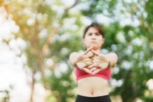 joven adulto hembra en rosado ropa de deporte extensión músculo en el parque exterior, deporte mujer calentar arriba Listo para corriendo y trotar en Mañana. bienestar, aptitud física, ejercicio y trabajo vida equilibrar conceptos foto