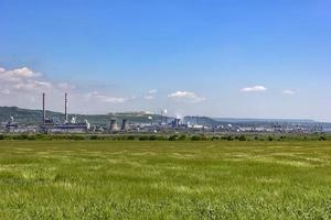 day view of a factory in the middle of a green rice field. Factory pipes polluting air on a silent. photo