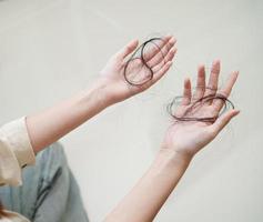 Asian woman have problem with long hair loss attach in her hand. photo