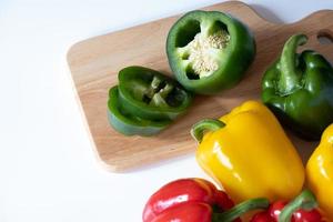 Top view of cutting sweet bell pepper on the wooden board isolated on white background. photo