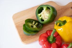 Top view of cutting sweet bell pepper on the wooden board isolated on white background. photo