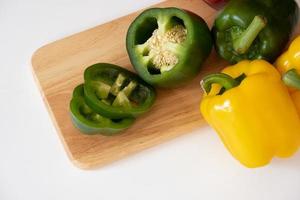 Top view of cutting sweet bell pepper on the wooden board isolated on white background. photo