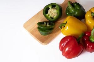 Top view of cutting sweet bell pepper on the wooden board isolated on white background. photo