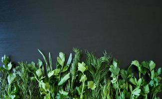 photo greenery on a dark wooden background, healthy food, twigs of plants, bottom