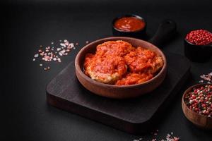 Delicious fresh cutlets or meatballs with spices, herbs and tomato sauce photo