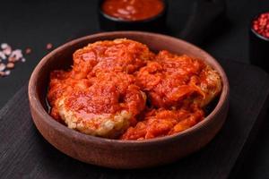 Delicious fresh cutlets or meatballs with spices, herbs and tomato sauce photo