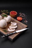 Fresh raw champignon mushrooms on a wooden cutting board with spices photo