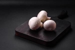 Fresh raw champignon mushrooms on a wooden cutting board with spices photo