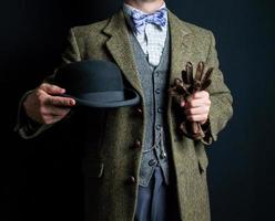 Portrait of Man in Tweed Suit Holding Bowler Hat on Black Background. Vintage Style and Retro Fashion of English Gentleman. photo
