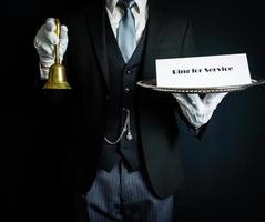 retrato de mayordomo con traje formal oscuro y guantes blancos con campana y cartel. anillo de servicio. concepto de hospitalidad profesional. foto