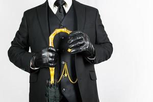 Portrait of Gentleman in Dark Suit and Leather Gloves Holding an Umbrella on White Background. Vintage Style and Retro Fashion. photo