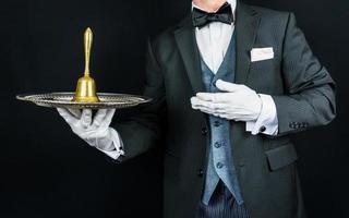 retrato de mayordomo o conserje en blanco guantes participación oro campana en plata bandeja. concepto de profesional hospitalidad. anillo para servicio.