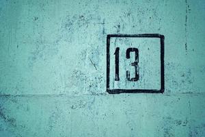 number 13 is stenciled in black frame on green concrete wall, copy space photo