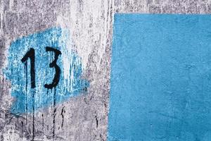 number 13 painted on dirty concrete wall on the corner of old abandoned house photo