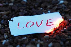 Paper note with word love burning at dusk. End of love story and breakup idea photo