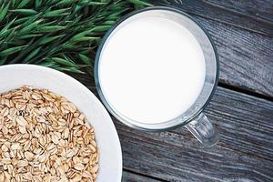 Oatmeal milk and green oats on wooden table, copy space photo