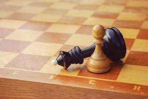 final of chess game, black king defeated by white pawn, good vs evil photo