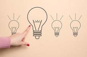 A drawn light bulb and a female hand pointing at it, concept of searching for new ideas, innovation photo