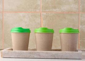 Paper brown cups with a plastic green lid for coffee and tea photo