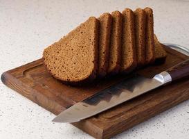 Triangular rye piece of bread on a wooden cutting board photo