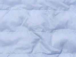 A fragment of blue fabric with down filling and stitching, fabric for jackets and coats photo