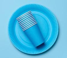 Round disposable blue paper plates and cups for a picnic, recyclable waste, top view. photo